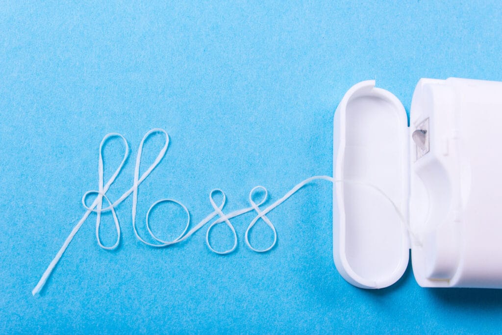 Dental floss and dispenser on a blue background.